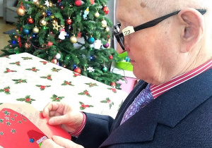 Mieszkaniec Domu Seniora czytający życzenia świąteczne